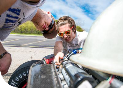 two students working on the SVSU race car